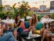 Group enjoying THC vape in a vibrant rooftop garden with city lights.